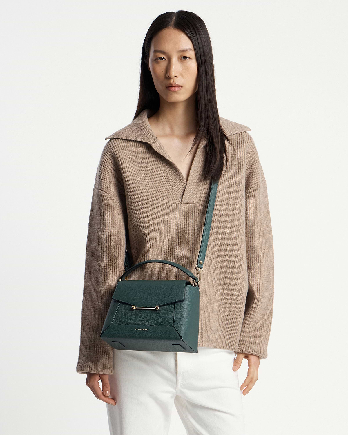 Model wearing Strathberry bottle green mosaic bag with top handle, shoulder strap, and gold bar.