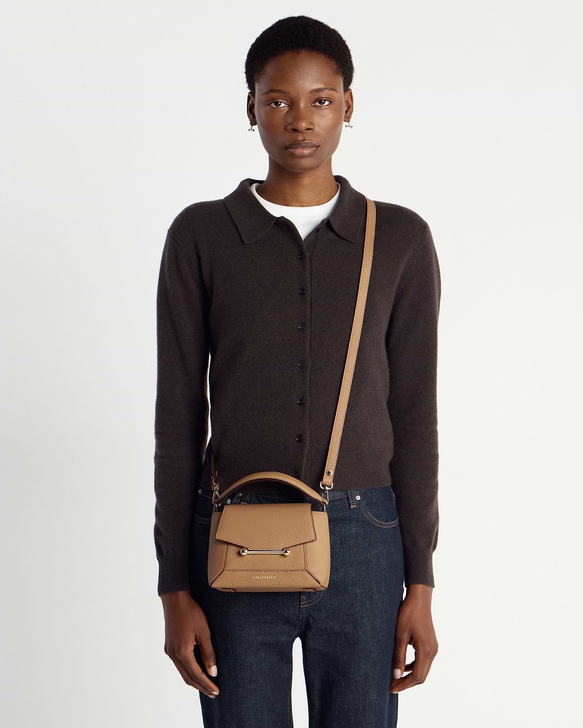 Model wearing a Strathberry Mosaic Nano caramel leather crossbody bag.