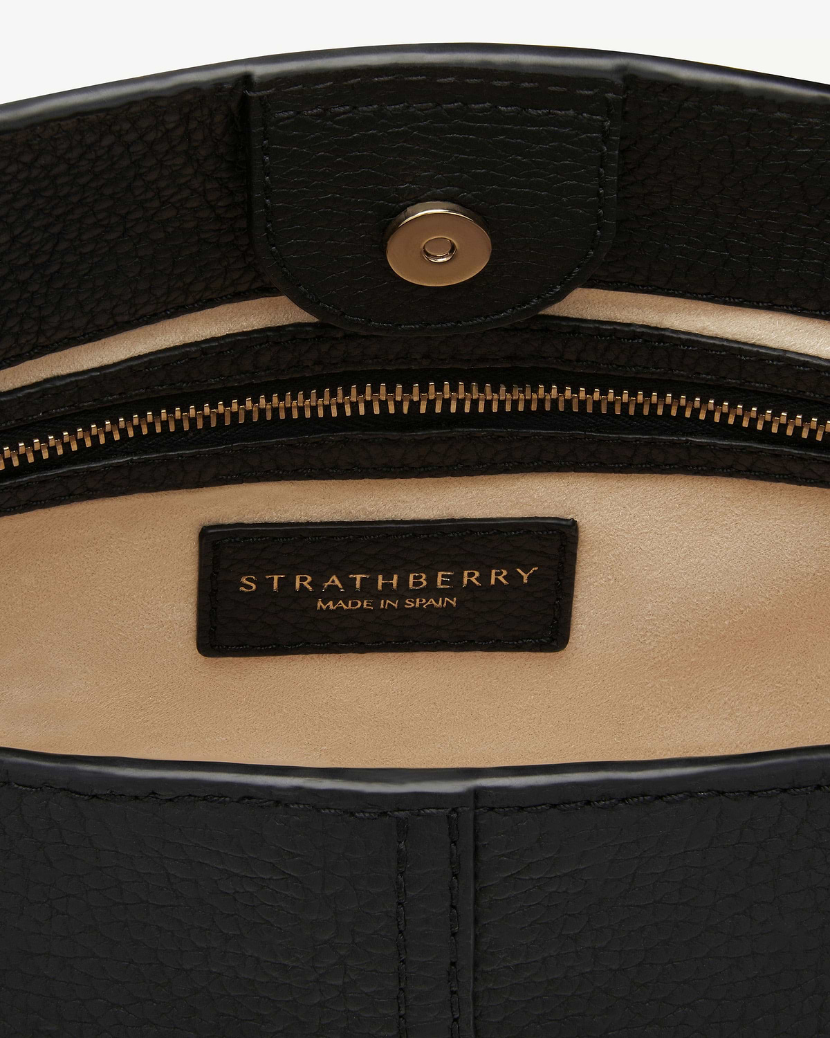Interior of black leather bag showing Strathberry label, zip and magnetic snap.