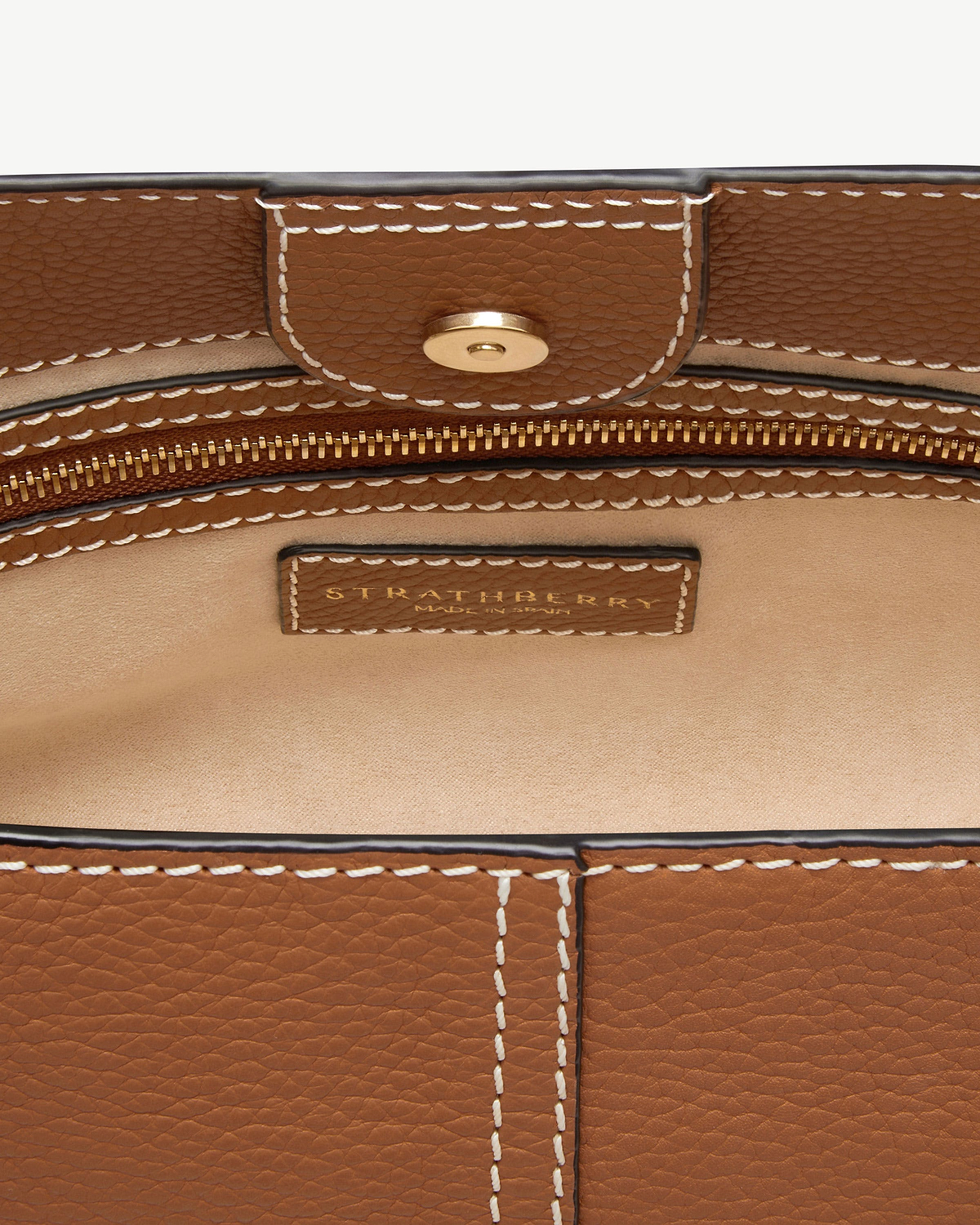 Tan pebbled leather interior with white stitching, gold zip and Strathberry label.