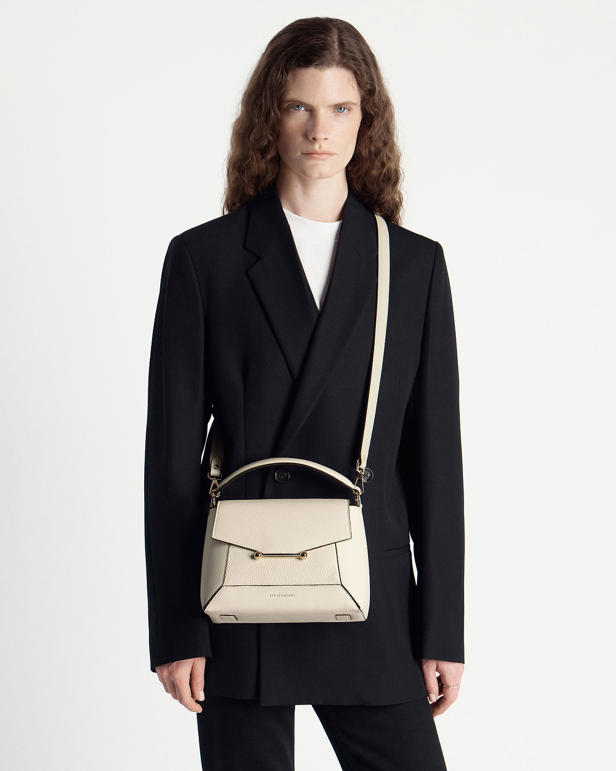 Model wearing black blazer with a vanilla Strathberry mosaic bag worn crossbody.