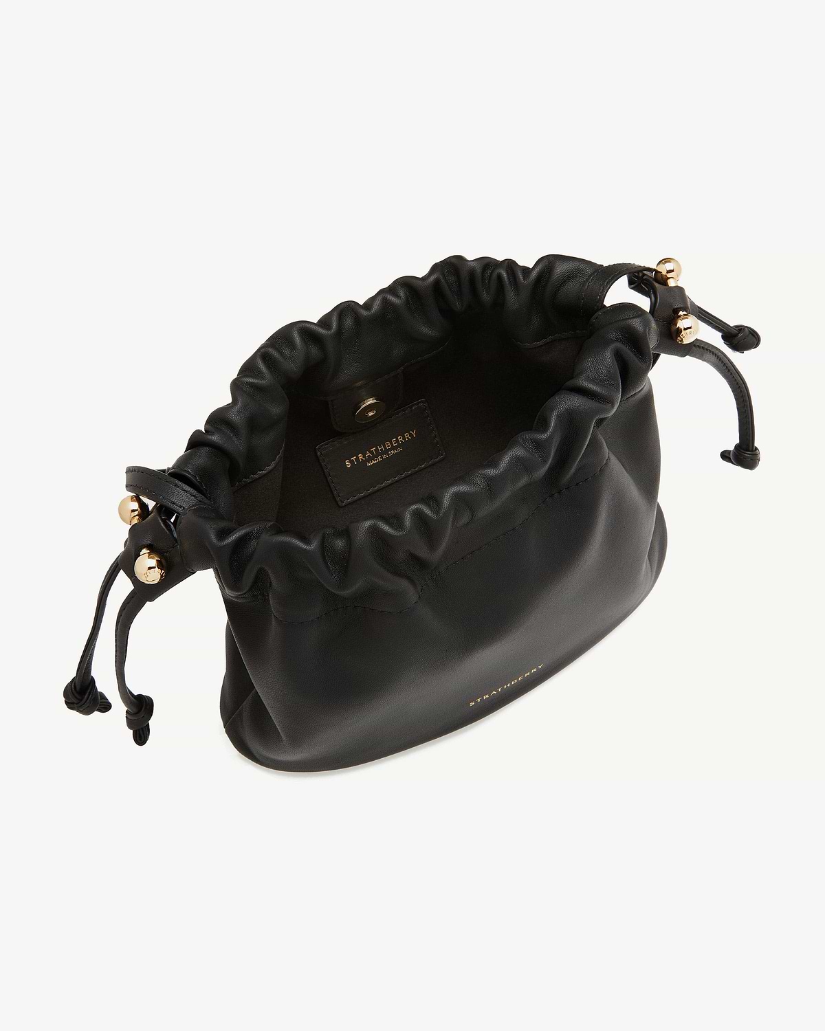 Strathberry Charlotte drawstring bag, black leather with gold hardware, open top.