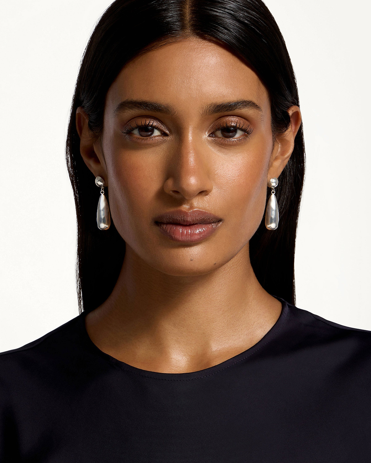 Woman wearing jasmine drop earrings in sterling silver against white background.