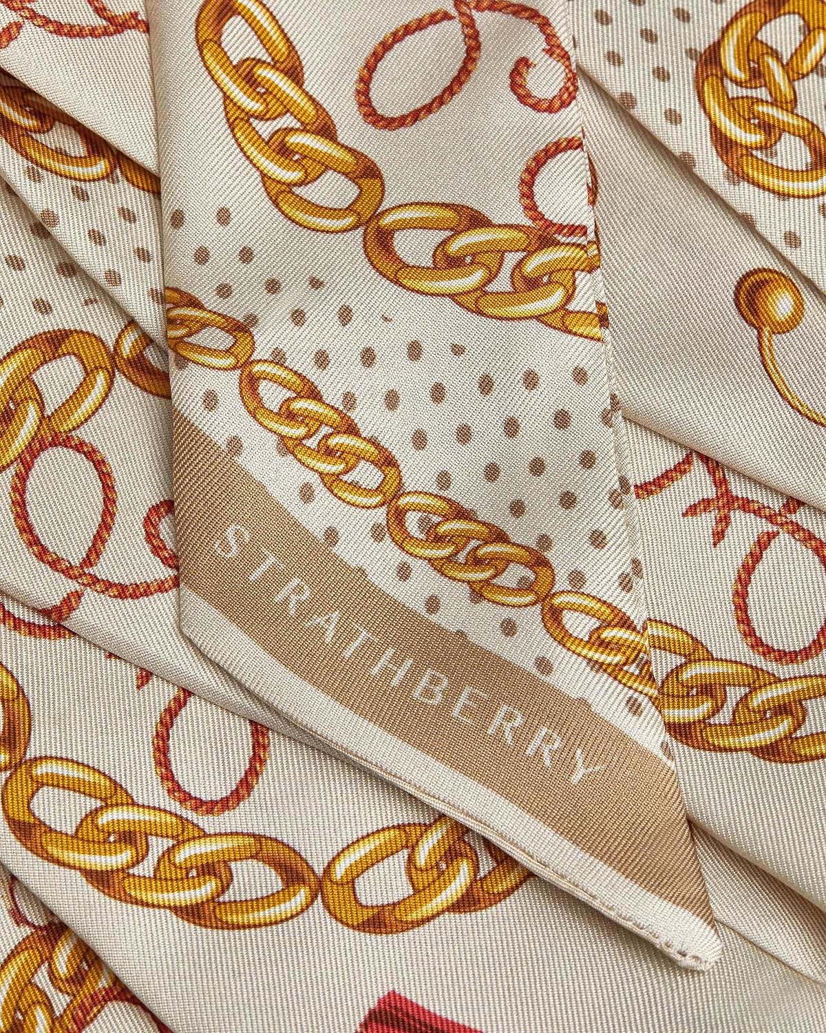 Caramel long silk skinny scarf with diamond chain print and visible Strathberry logo.