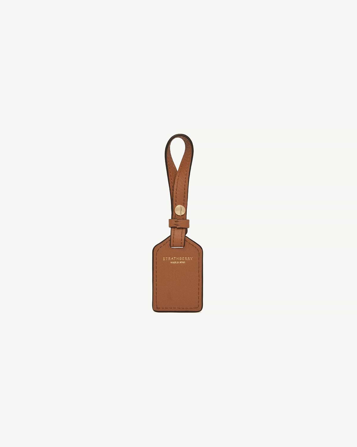 Tan leather tag with strap, gold rivet and Strathberry logo.