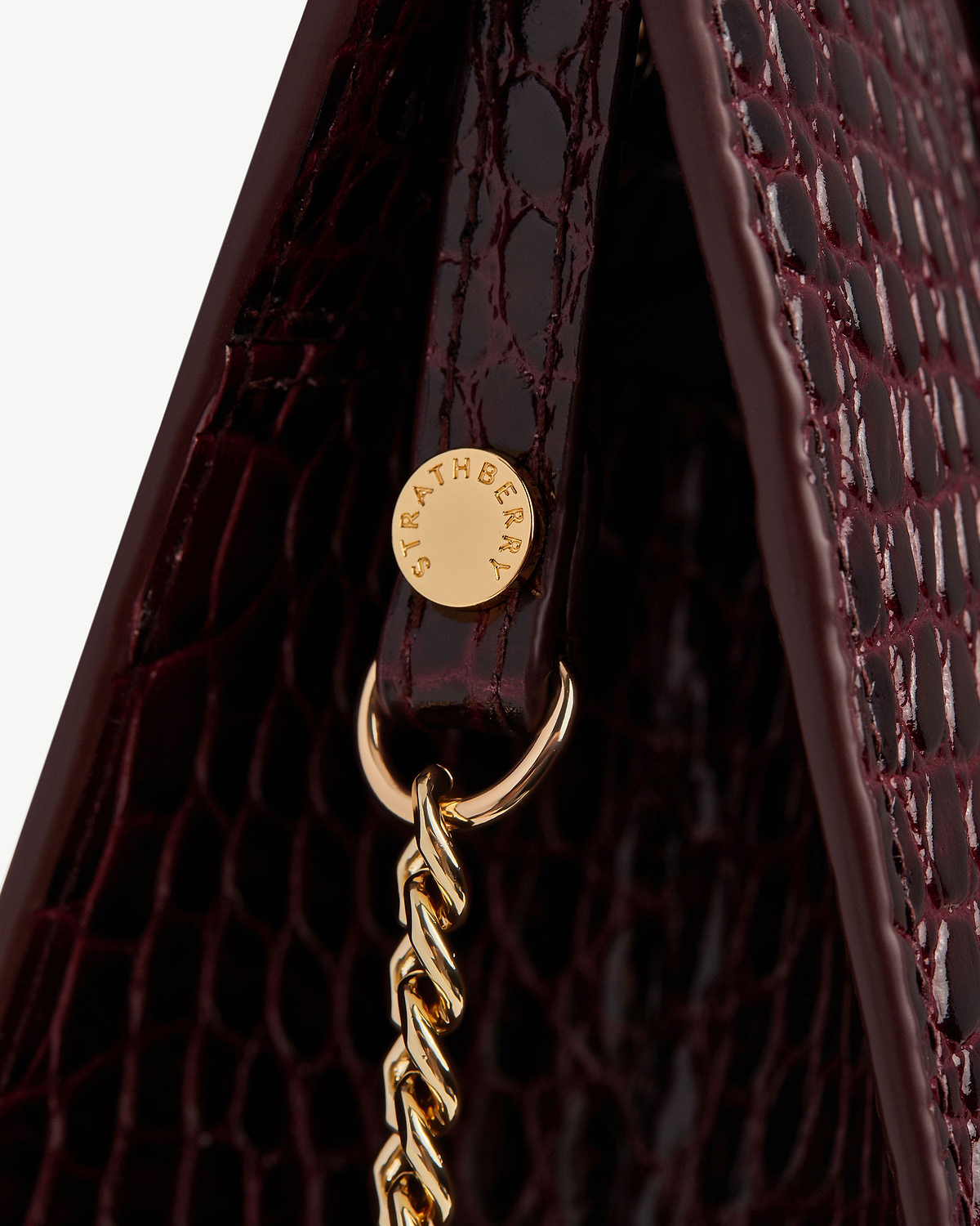 Close-up of croc-effect mini tote side with gold Strathberry rivet and chain.
