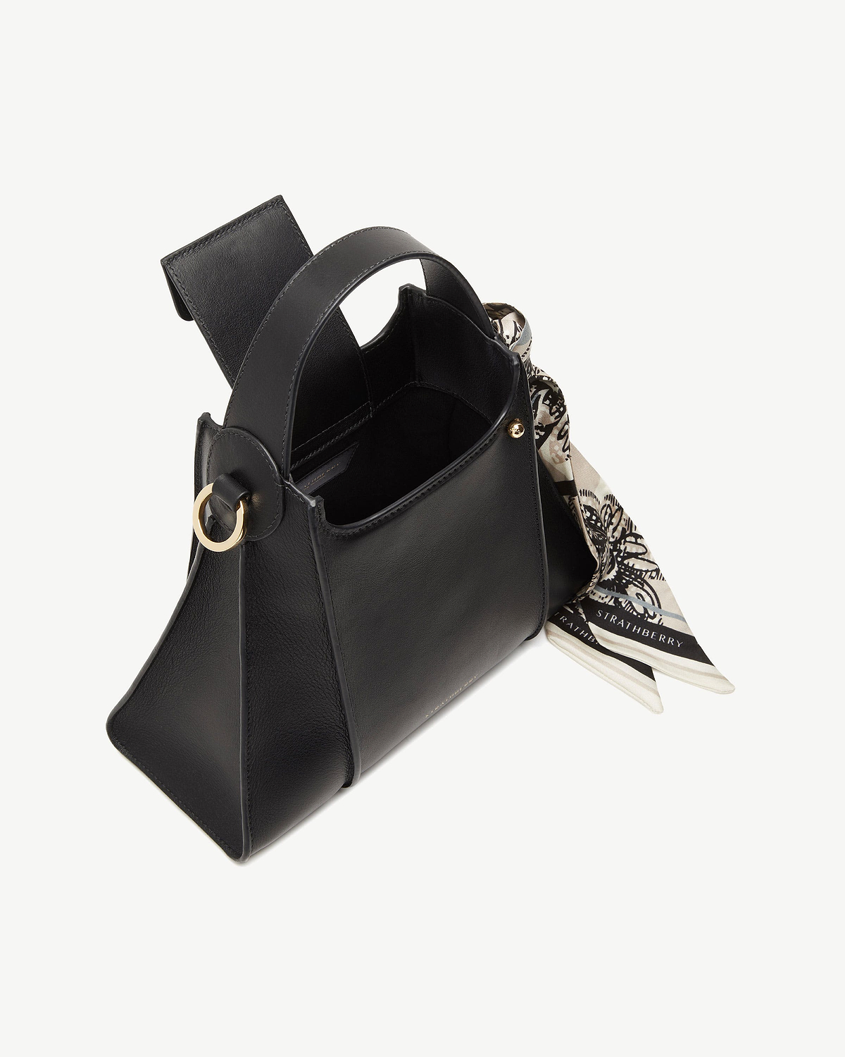 Black Arkshell handbag with top handle, gold ring detail and patterned Strathberry scarf.