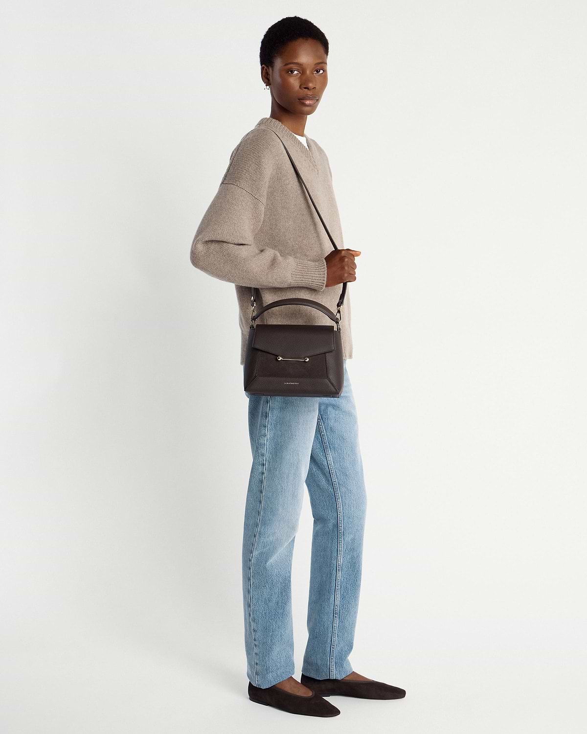 Woman wearing beige jumper and jeans carrying dark chocolate suede and leather mosaic bag.