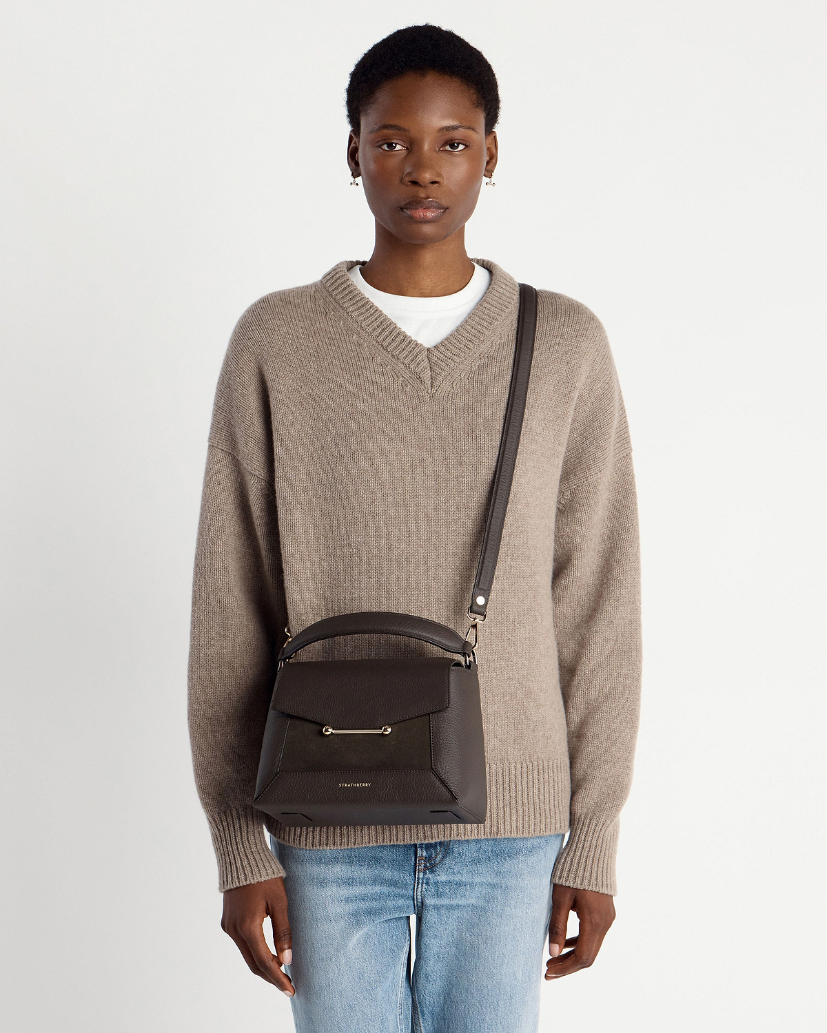 Model wearing dark chocolate mosaic bag by Strathberry with cross-body strap.