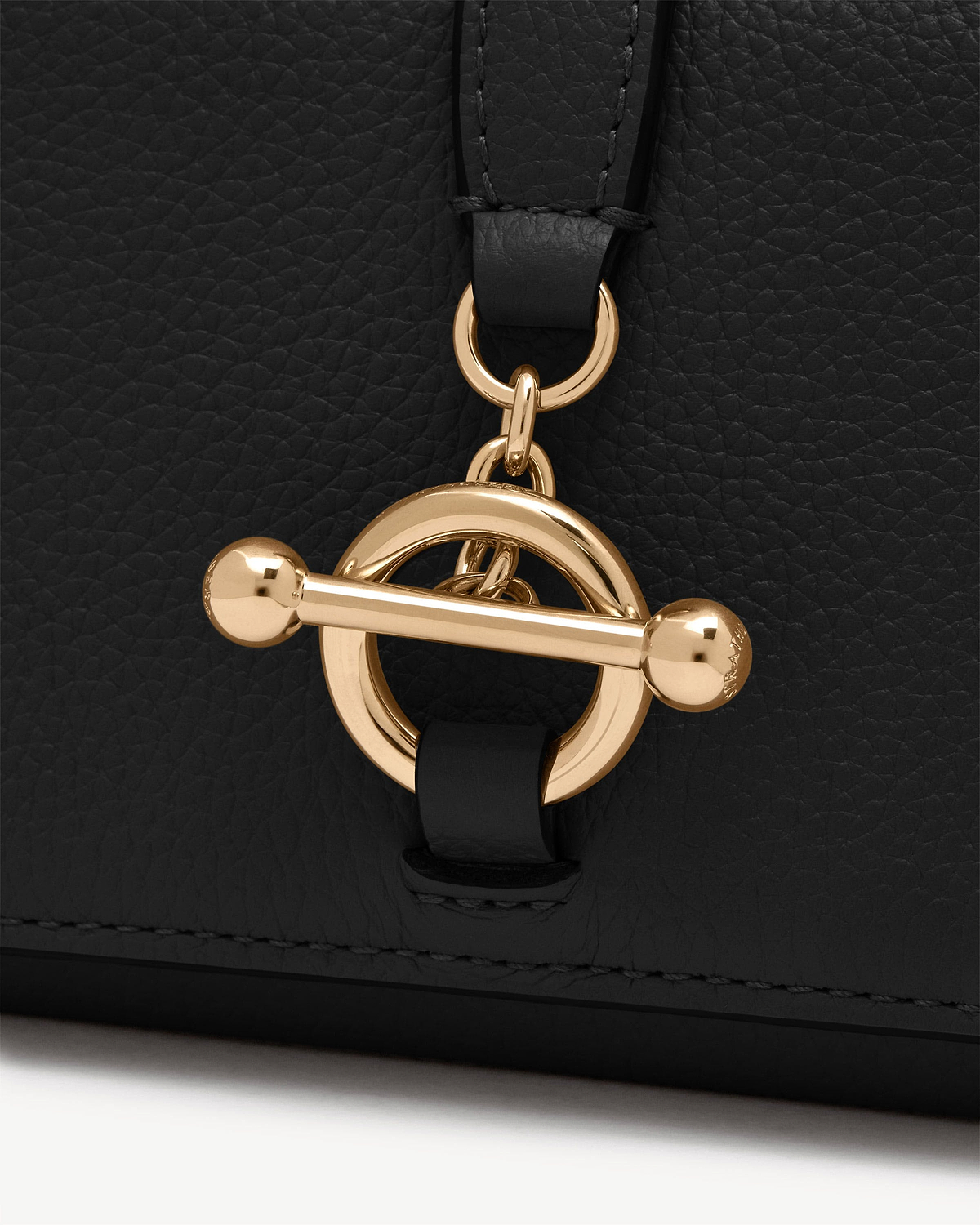 Black pebbled leather wallet with round gold toggle clasp detail.
