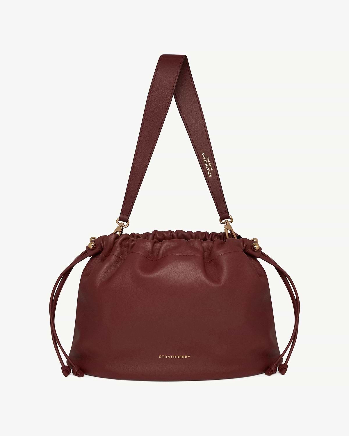 Oxblood Charlotte Midi drawstring bag with wide strap and gold Strathberry logo.