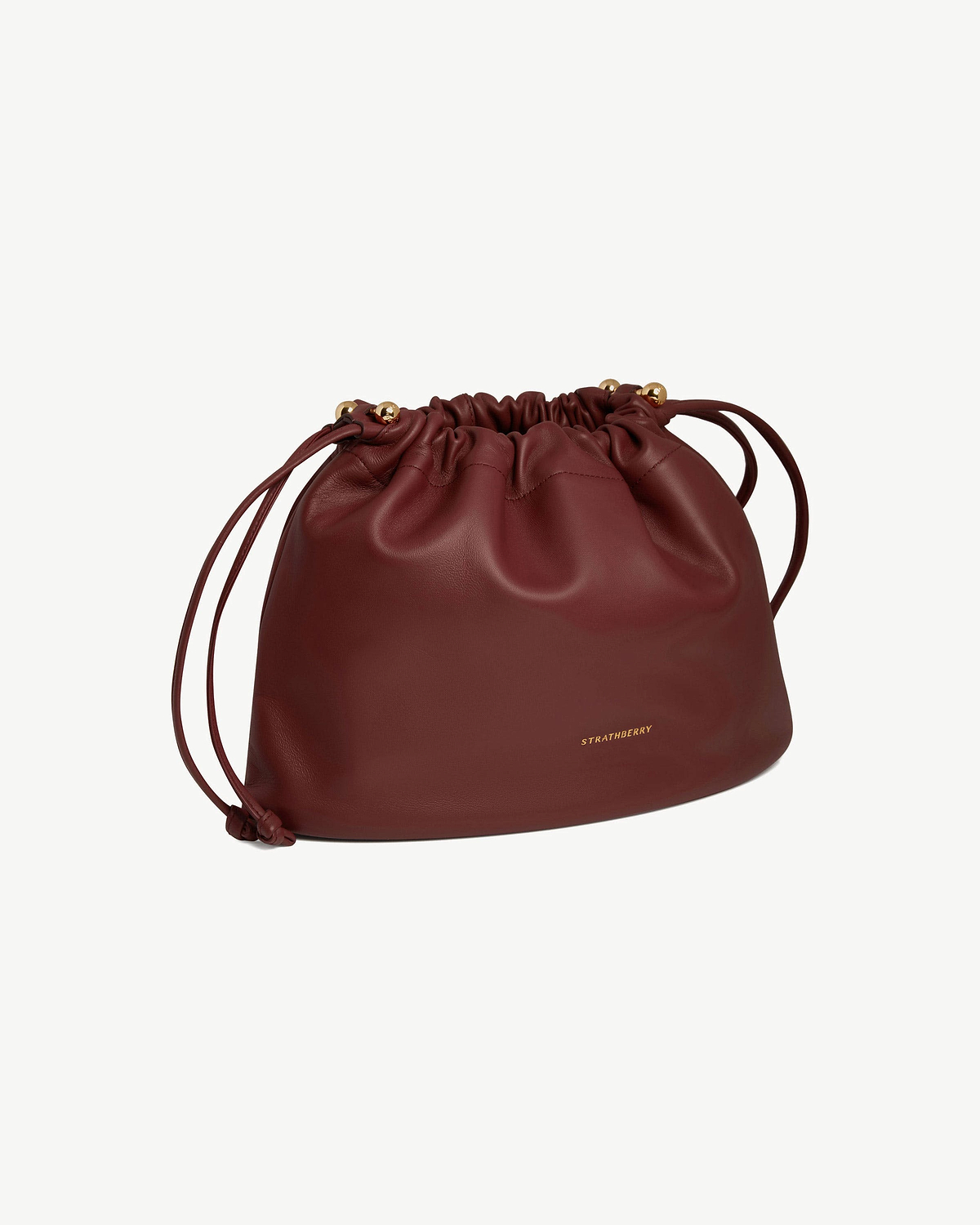Oxblood leather Charlotte Midi drawstring bag with gathered top and gold Strathberry logo.