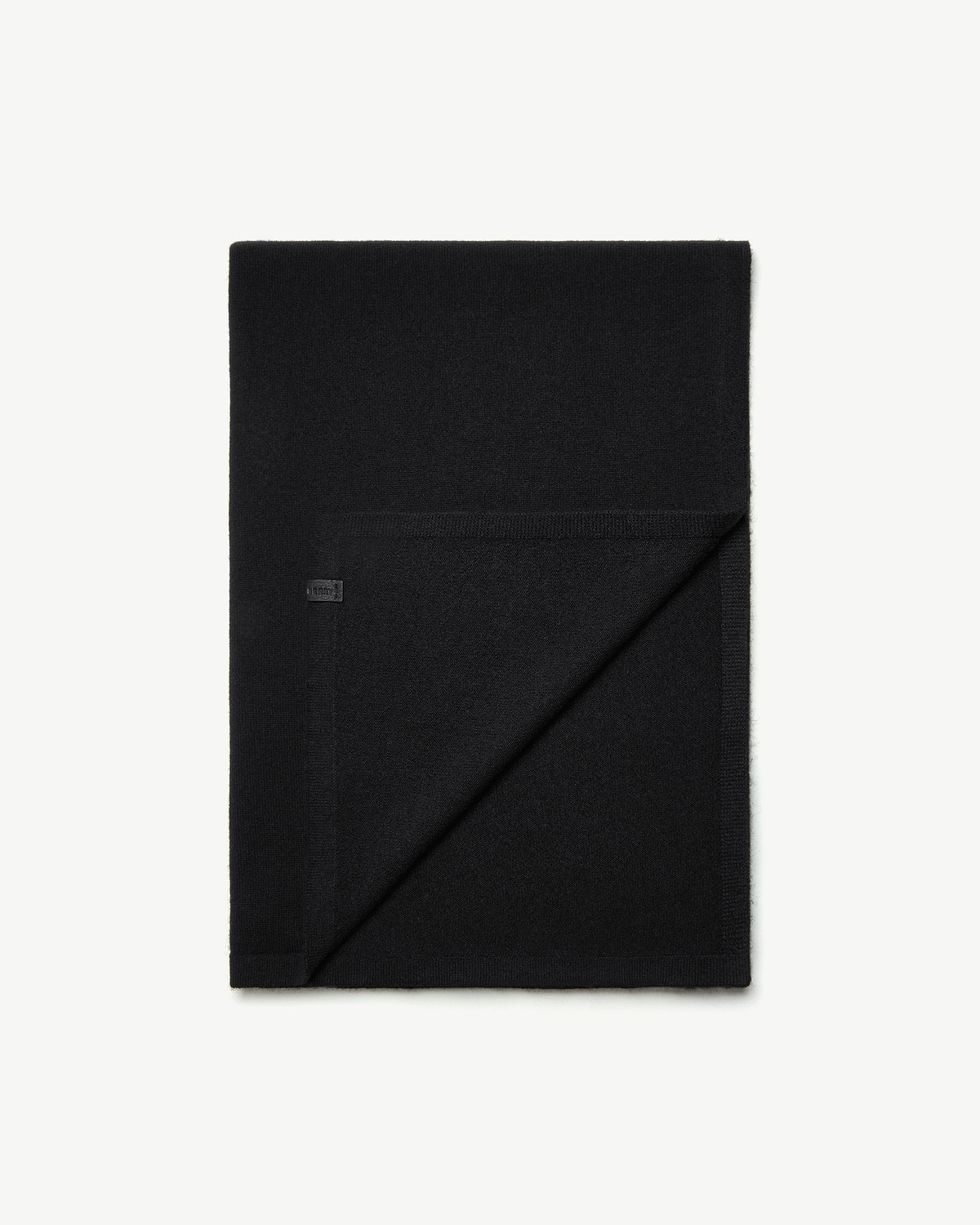 Black cashmere travel wrap folded, one corner turned to show the reverse side.