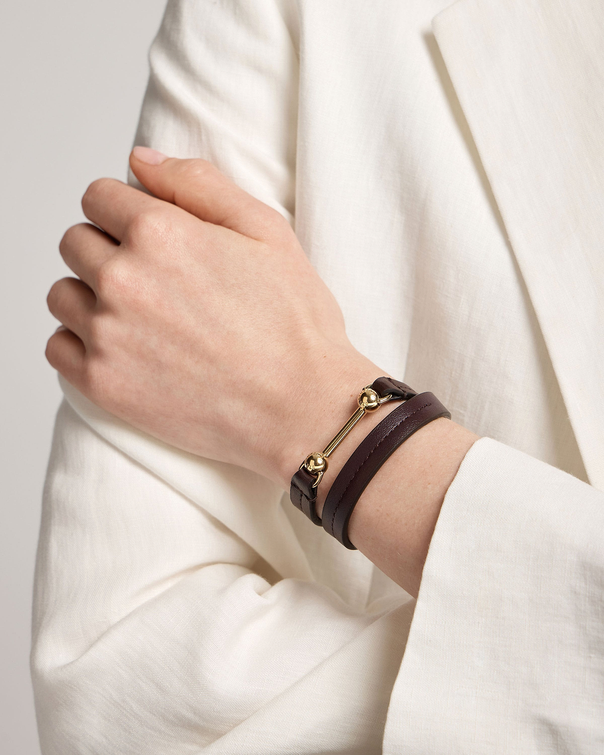 Burgundy double-wrap bracelet with gold bar and bead hardware on wrist.