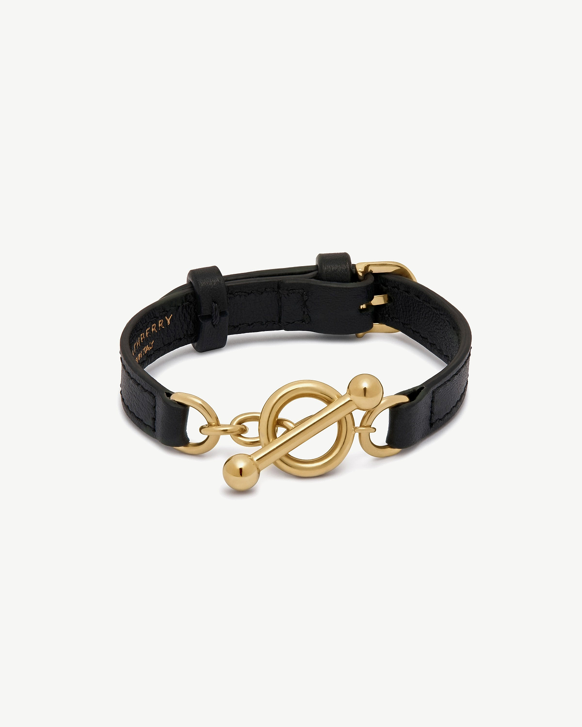 Black leather bracelet with gold circular toggle and bar fastening.