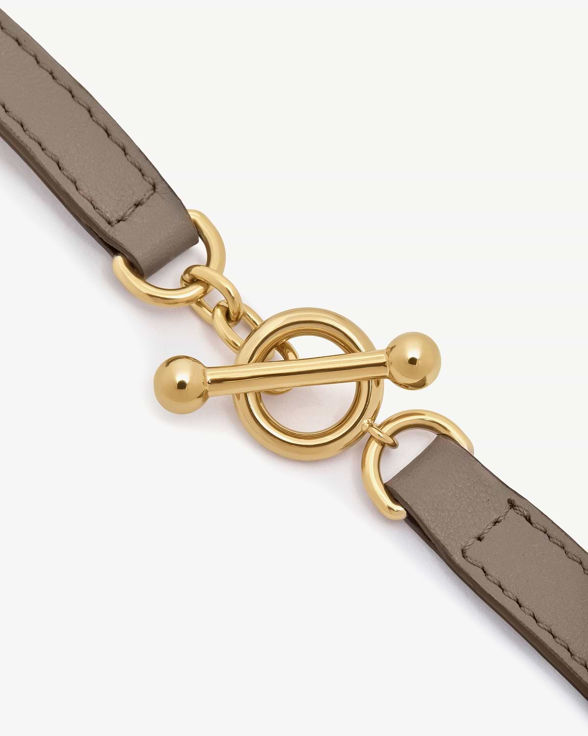 Taupe leather bracelet strap with gold toggle clasp and metal rings.