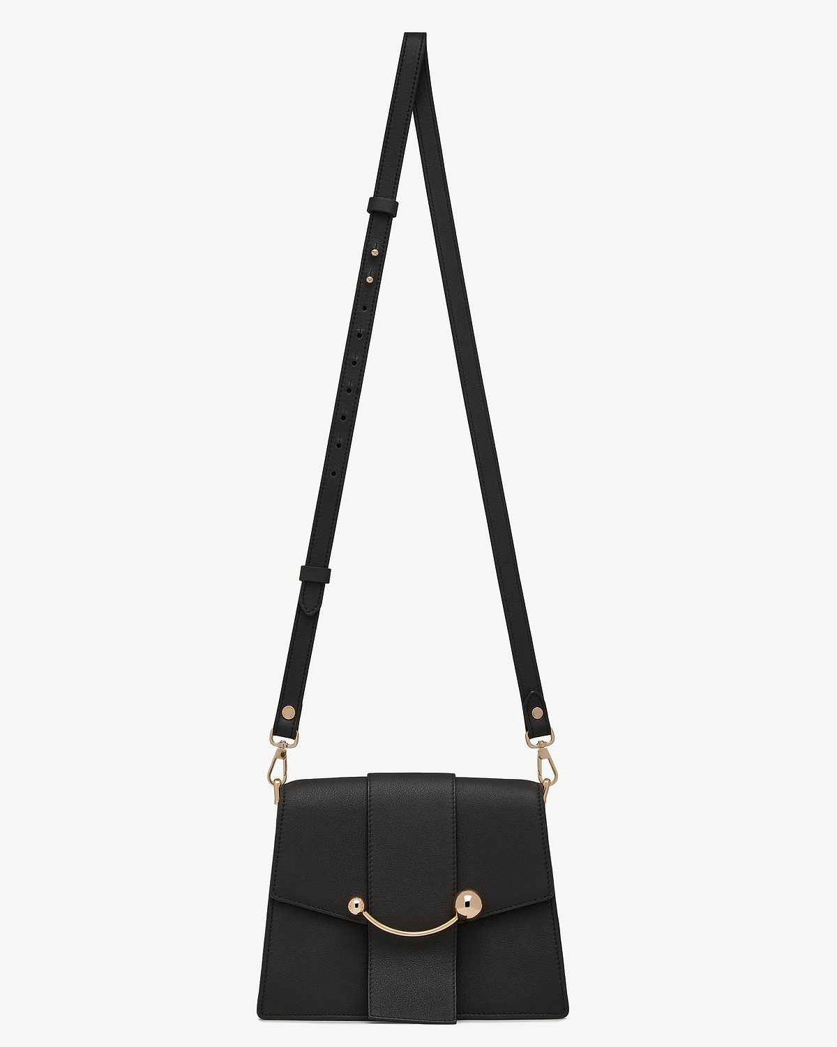 Black thin adjustable leather strap attached to small black crossbody bag with gold hardware
