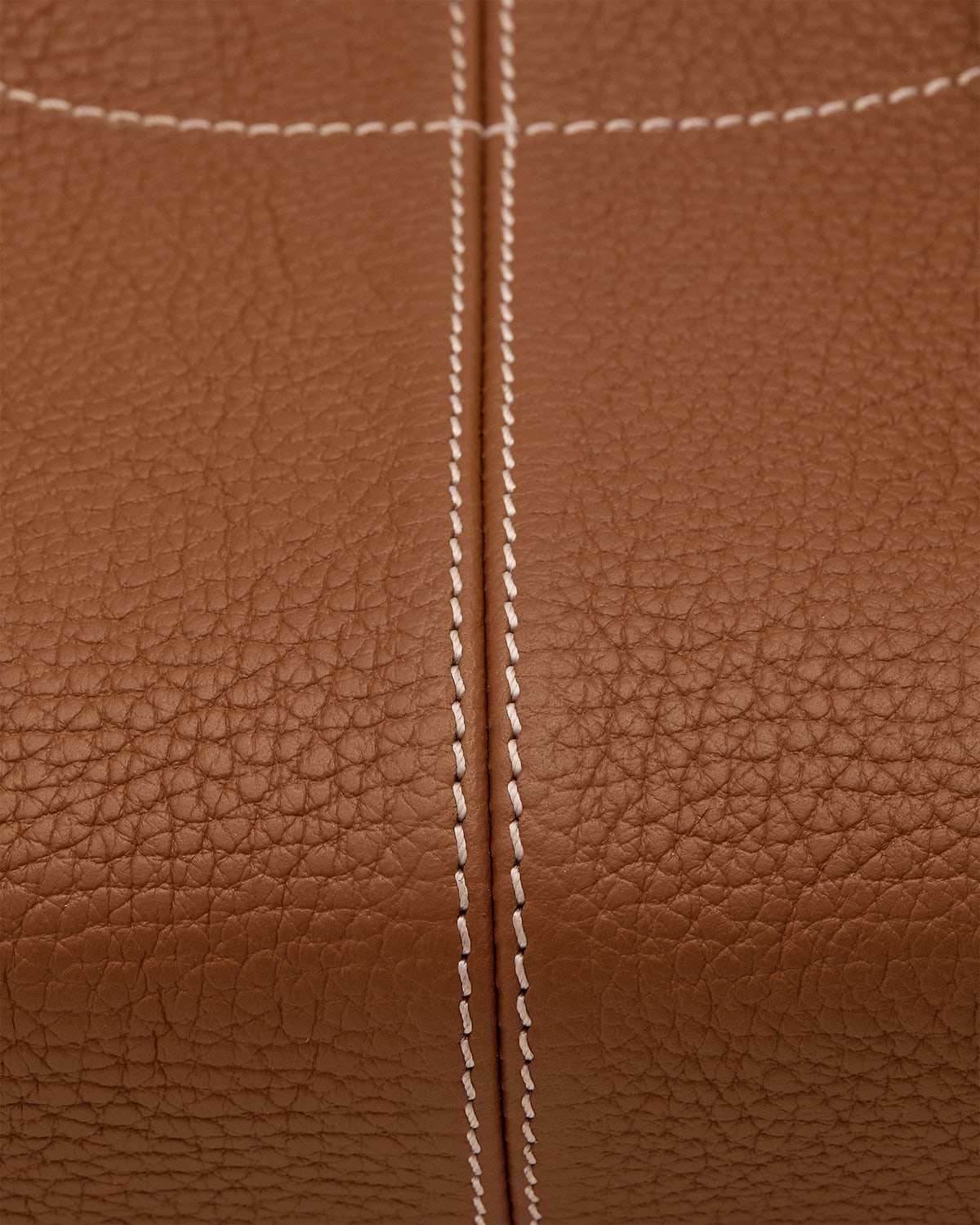 Close-up of tan pebbled leather with central double white stitched seam.