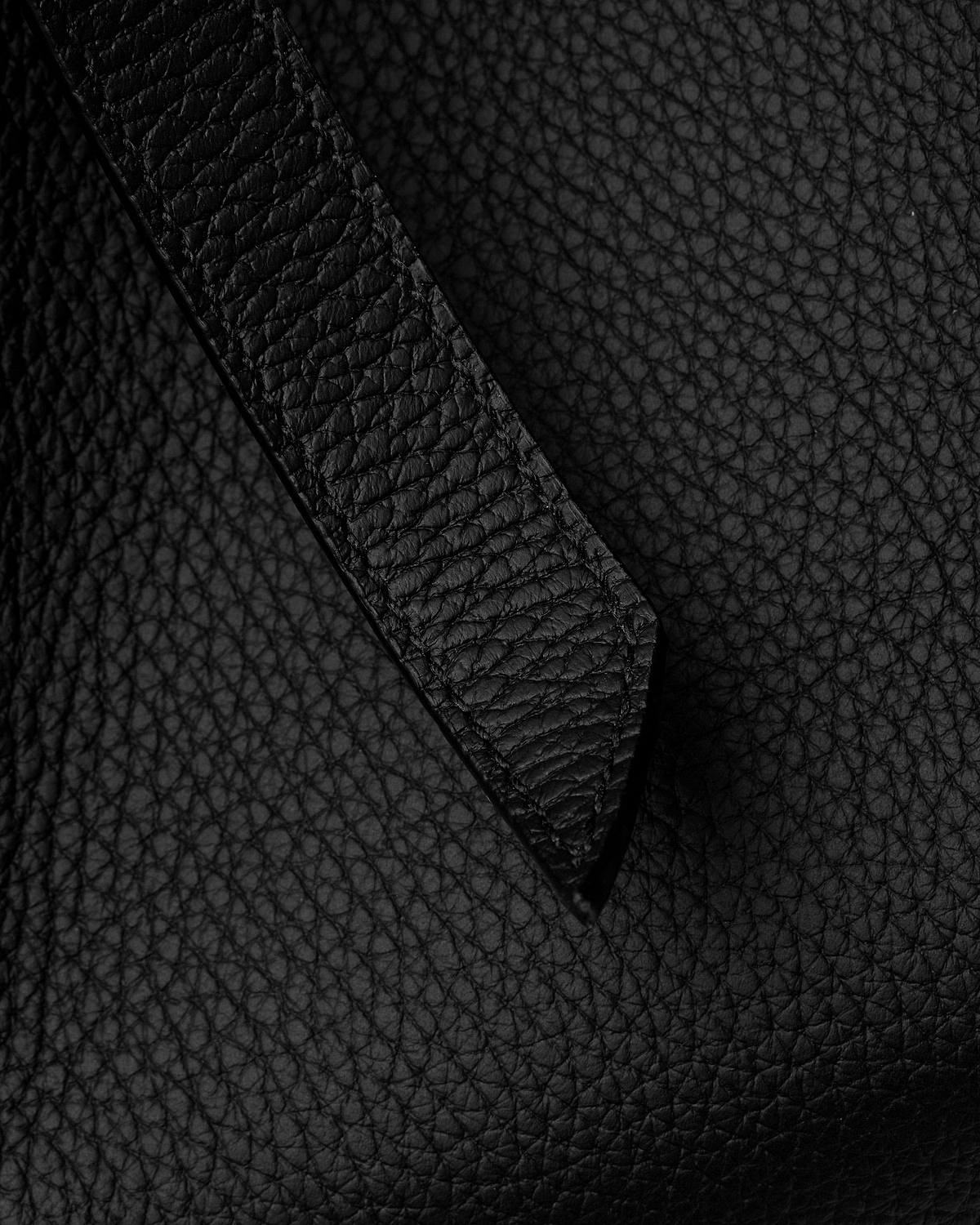 Close-up of black pebbled leather tote strap and body texture.