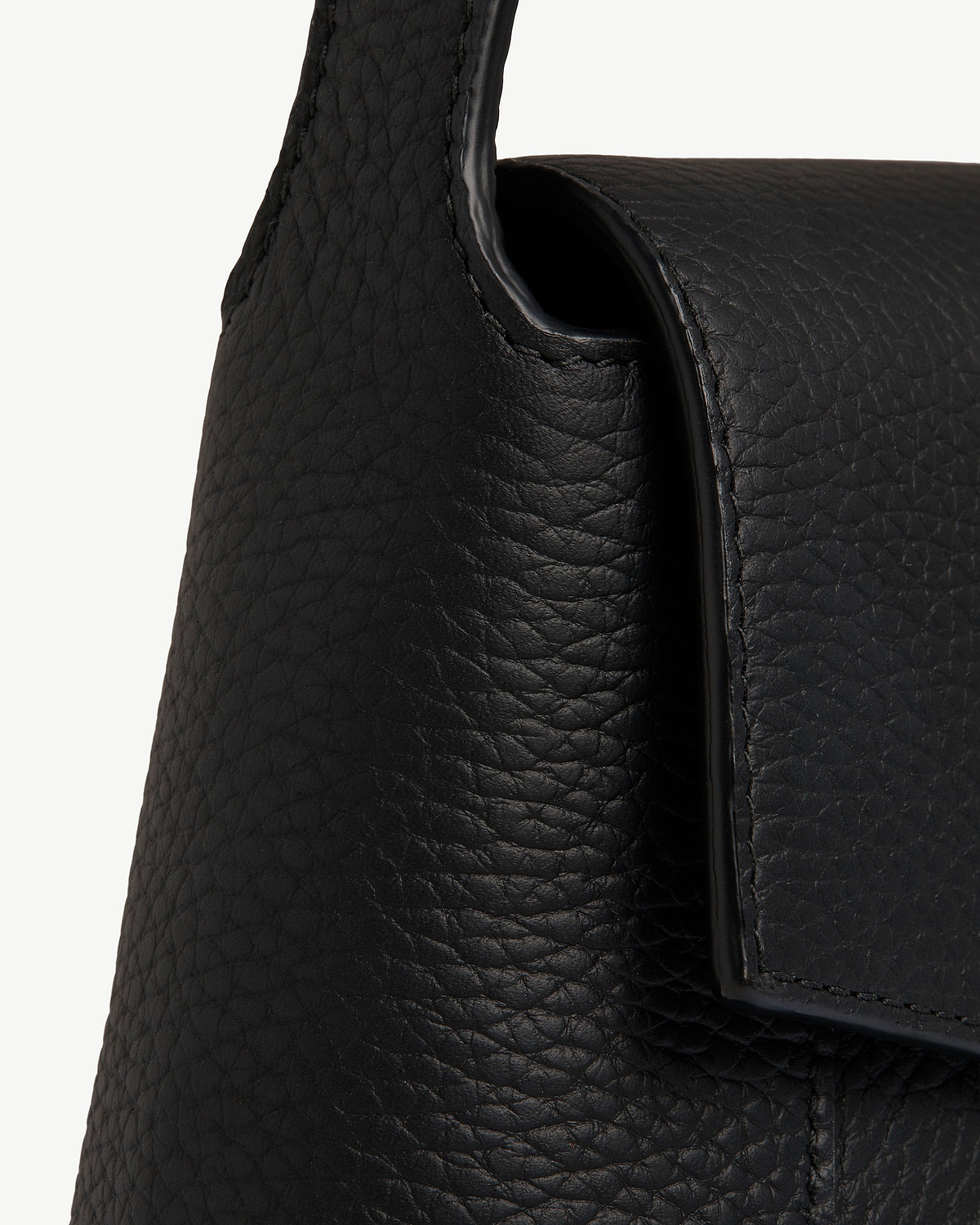 Black pebbled leather shoulder bag showing flap and strap edge.