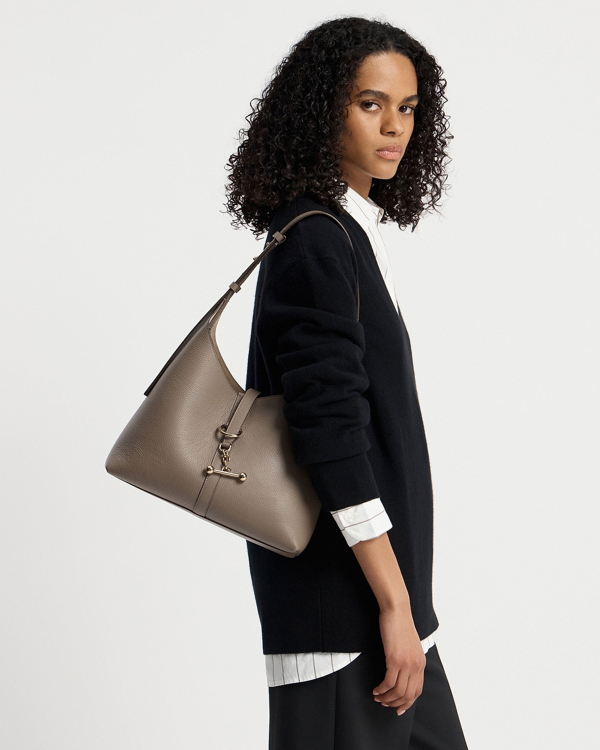 Woman wearing a black sweater carrying a taupe Kite Hobo shoulder bag.