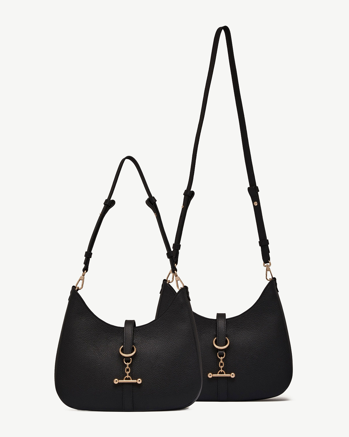 Two black kite sling bags with pebbled leather texture and gold hardware.