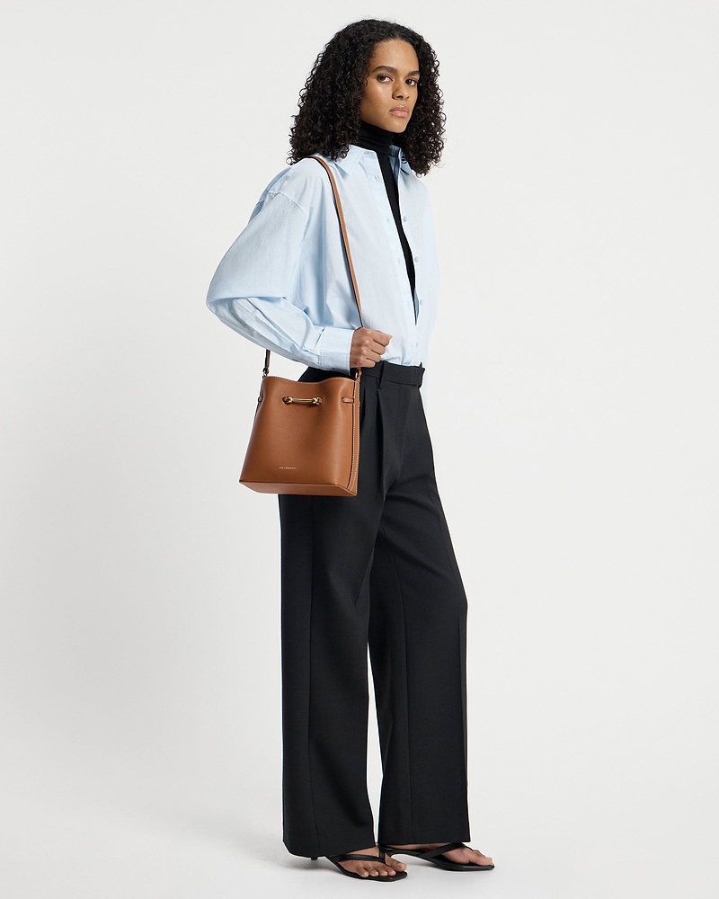 Model wearing chestnut Corda bucket bag over shoulder with light blue shirt.