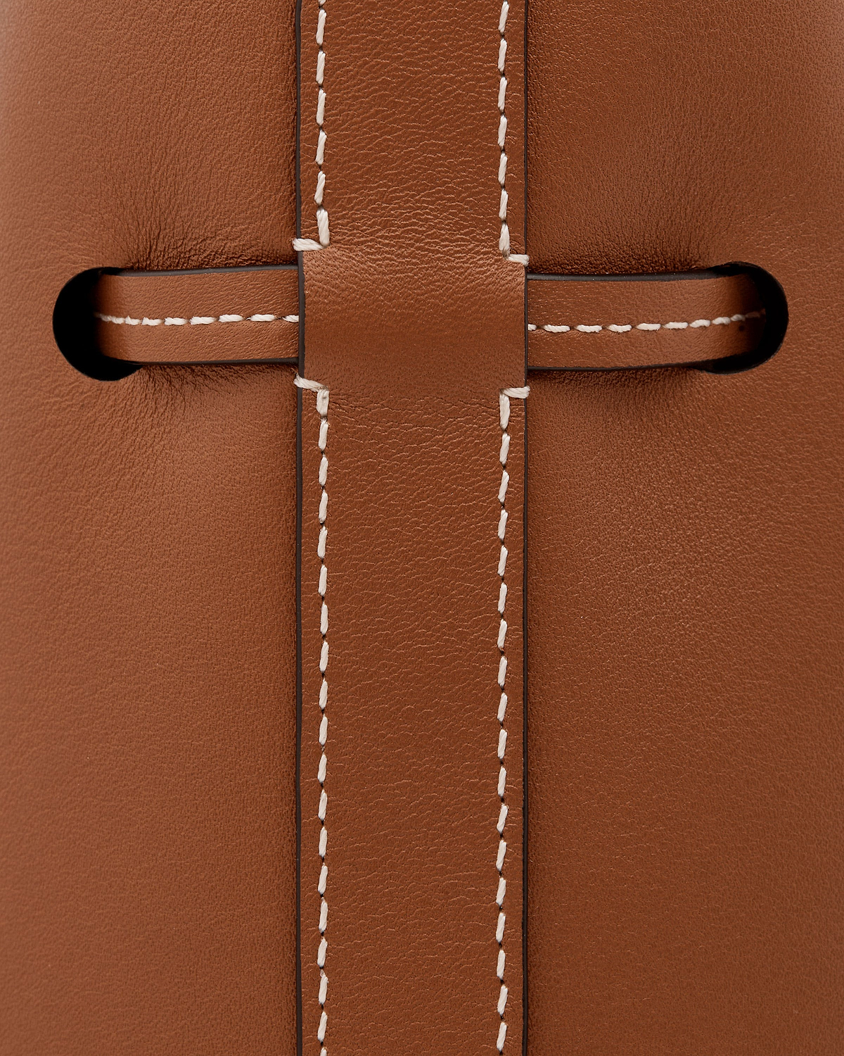 Chestnut leather strap threaded through slot with contrasting white stitching.
