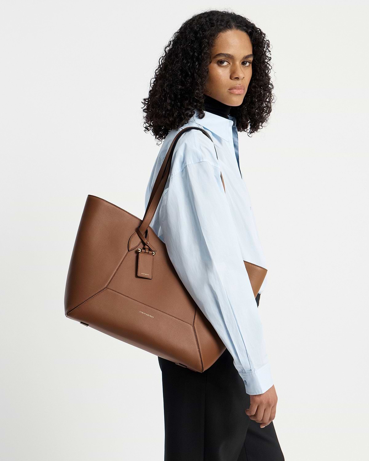Model wearing Strathberry hazelnut Mosaic Cabas tote over shoulder, light blue shirt.