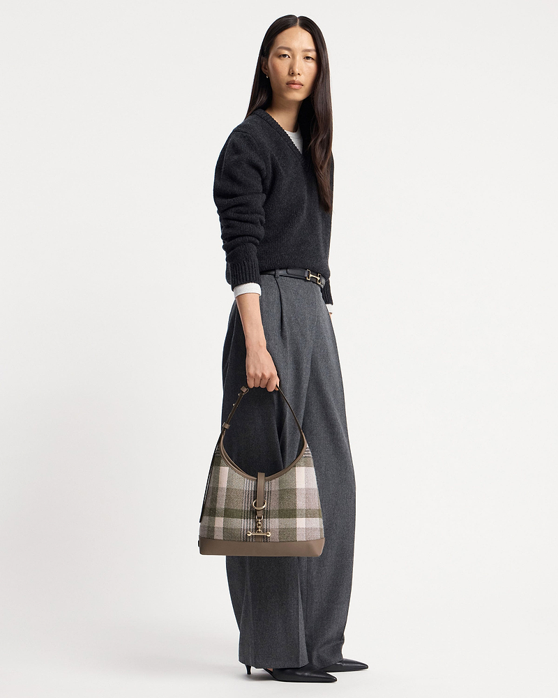 Model holding tartan taupe kite hobo bag with leather trim and gold hardware