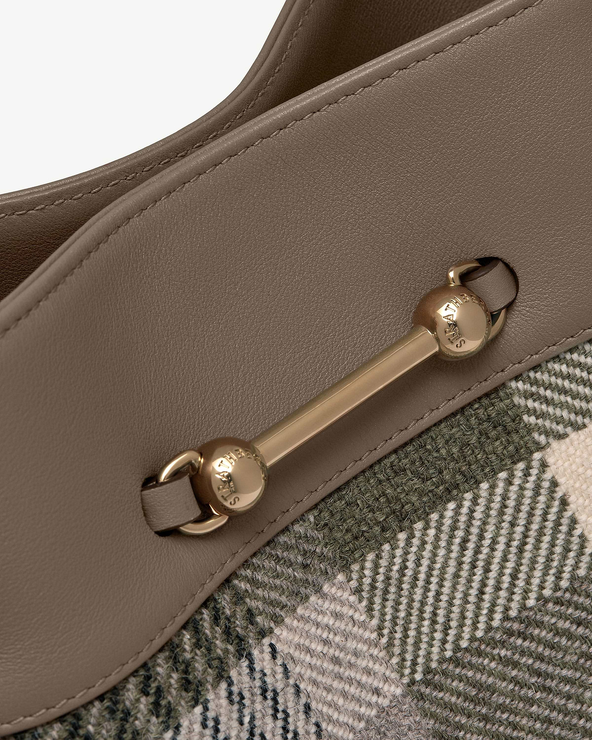 Taupe leather edge with gold Strathberry bar hardware on tartan fabric.