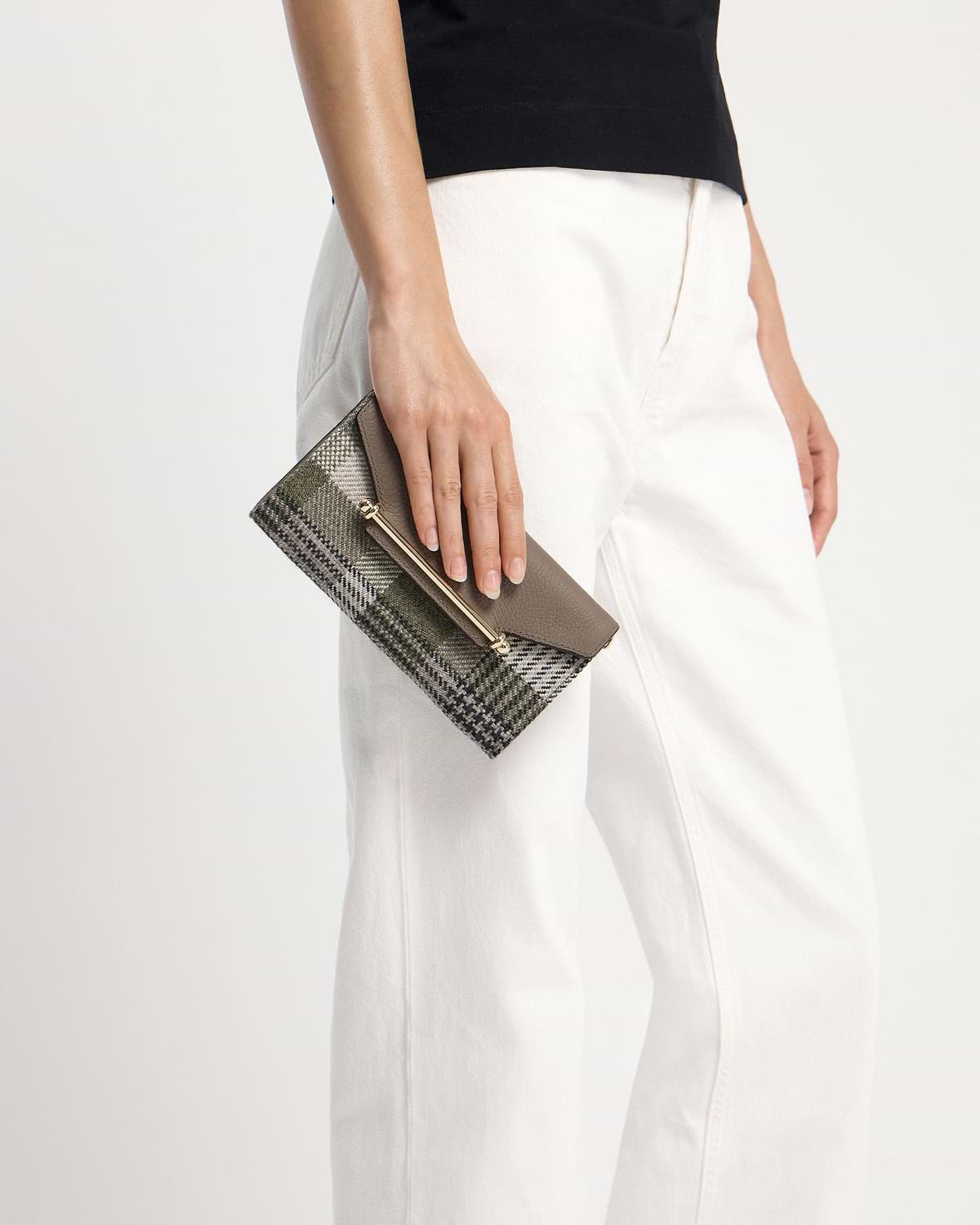 Model's hand holding a tartan taupe leather wallet with gold bar detail.