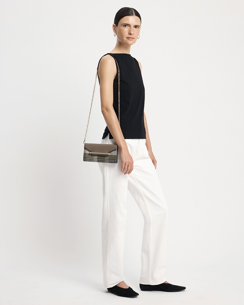 Model wearing a chain-strap tartan taupe wallet at her hip.