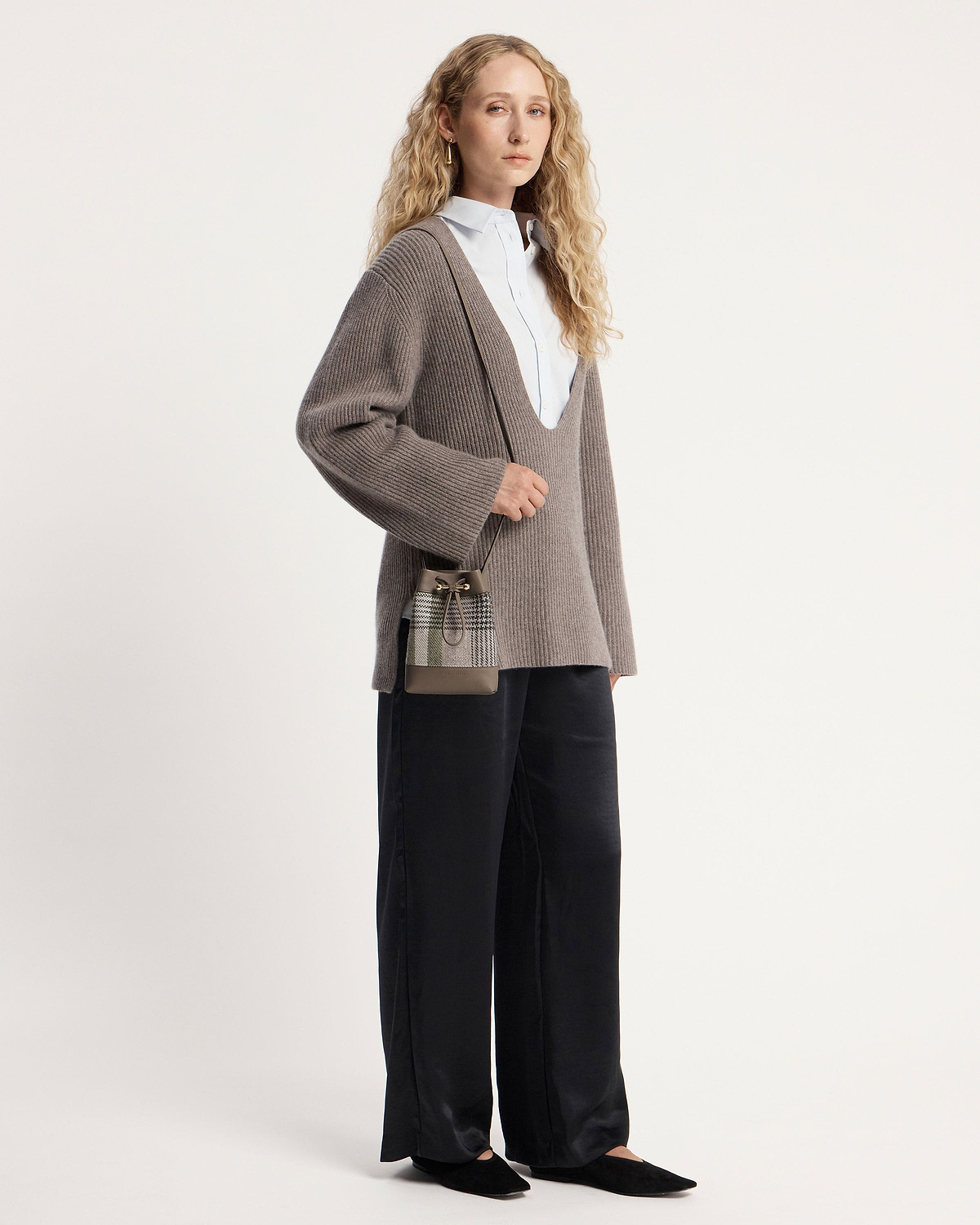 Woman wearing taupe ribbed jumper and tartan taupe midi pouch cross-body.