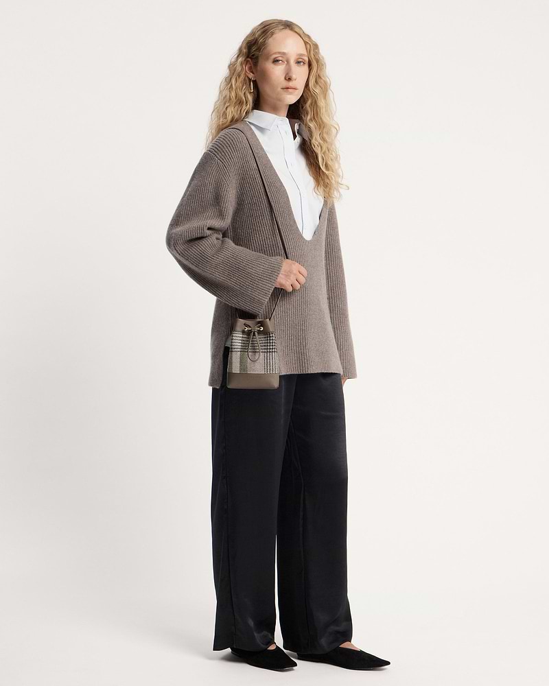 Woman wearing taupe ribbed jumper and tartan taupe midi pouch cross-body.