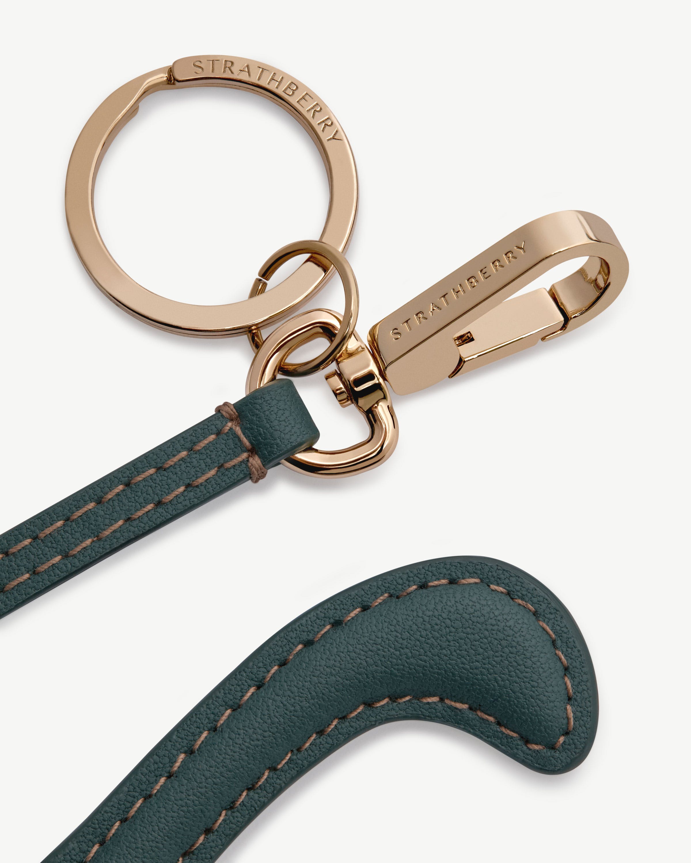 Bottle-green leather Nessie bag charm with contrast stitching and gold Strathberry hardware.