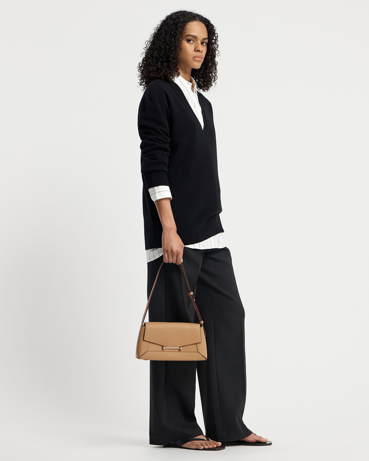 Model holding caramel mosaic shoulder bag with top handle and long strap.