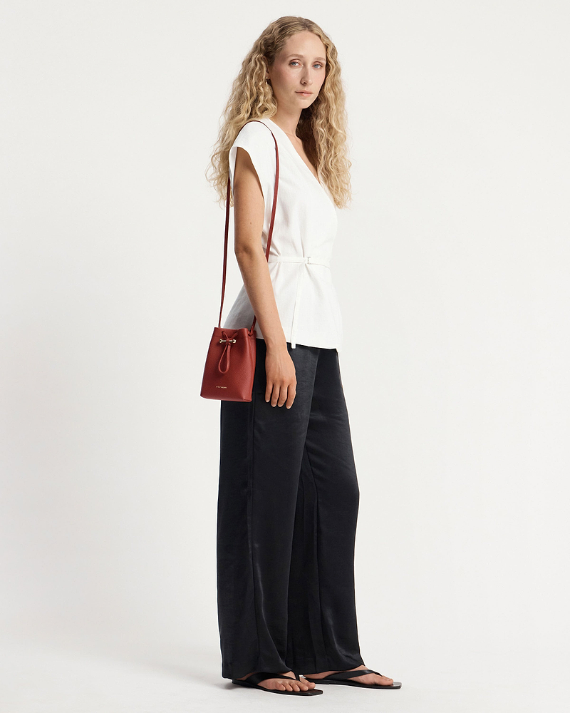 Model wearing a white top and black trousers with Levanto red Osette midi pouch.