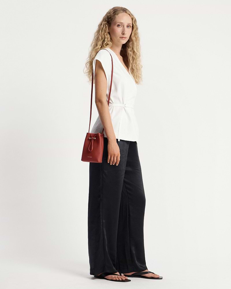 Model wearing a white top and black trousers with Levanto red Osette midi pouch.