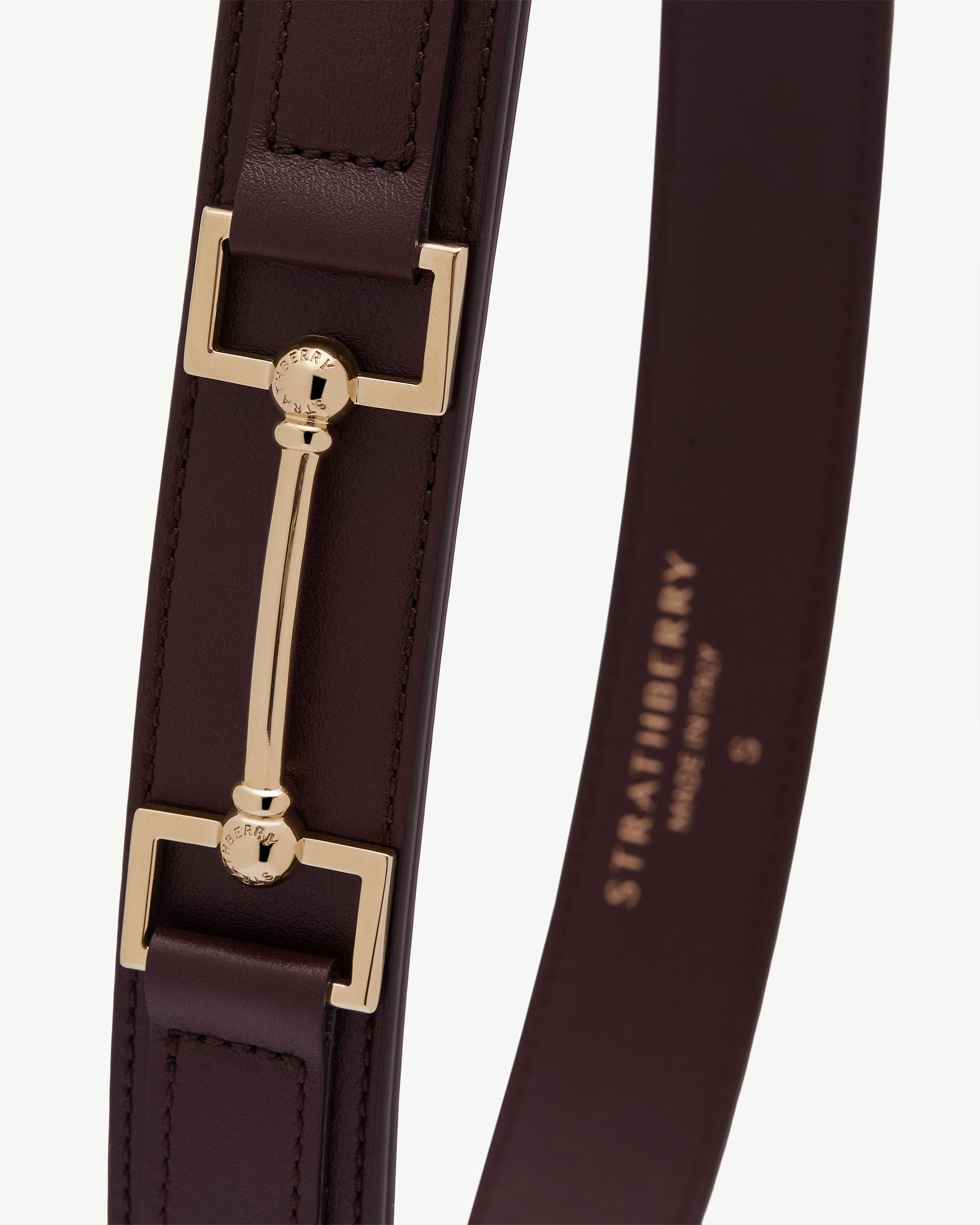 Burgundy Stockbridge belt strap showing gold Strathberry bar hardware and stitching