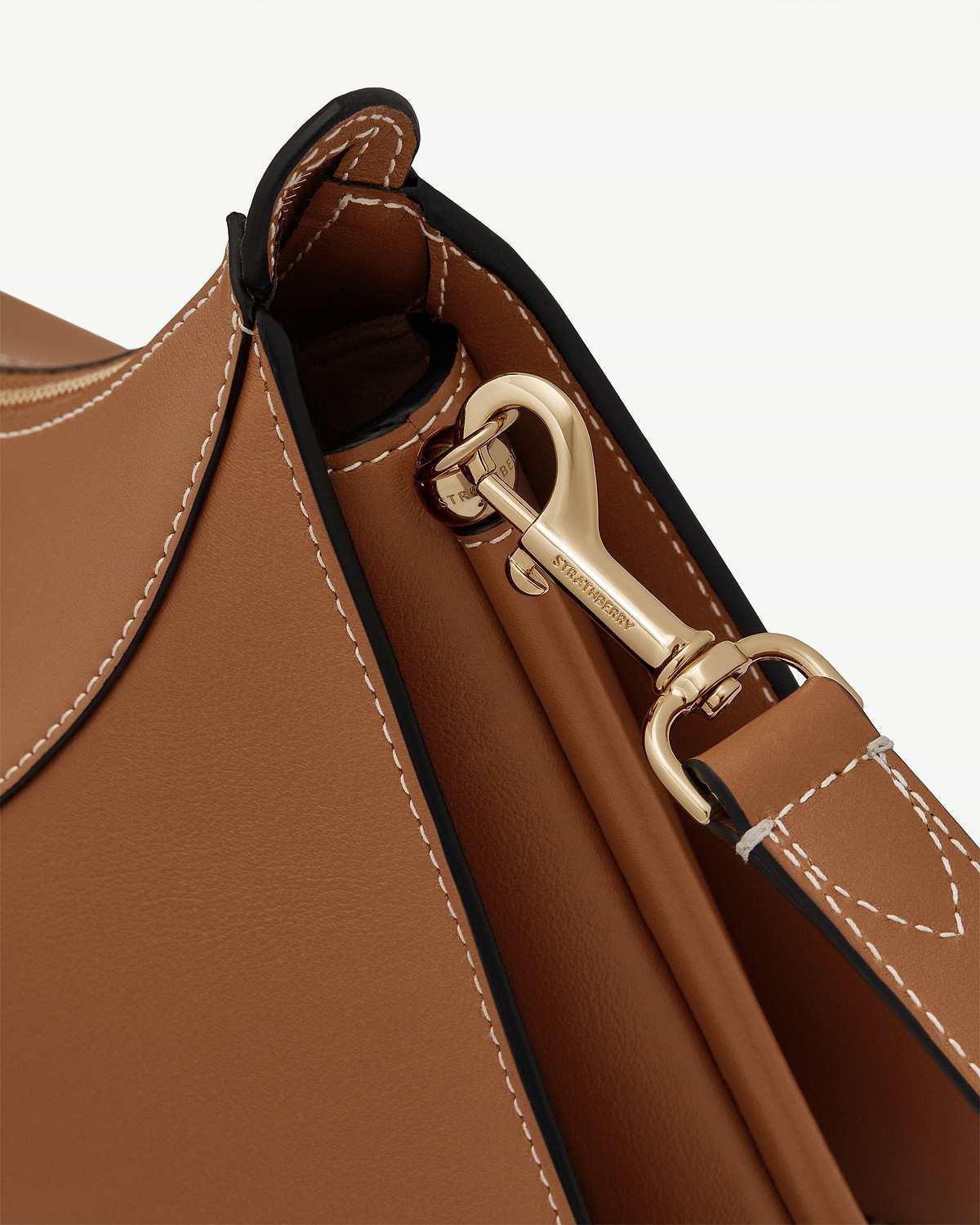 Detail of tan leather Nest Shoulder bag showing stitched edge and gold Strathberry clasp.