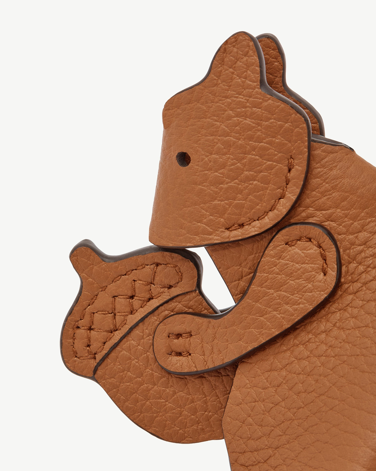Tan squirrel leather bag charm with stitched edges and textured grain.