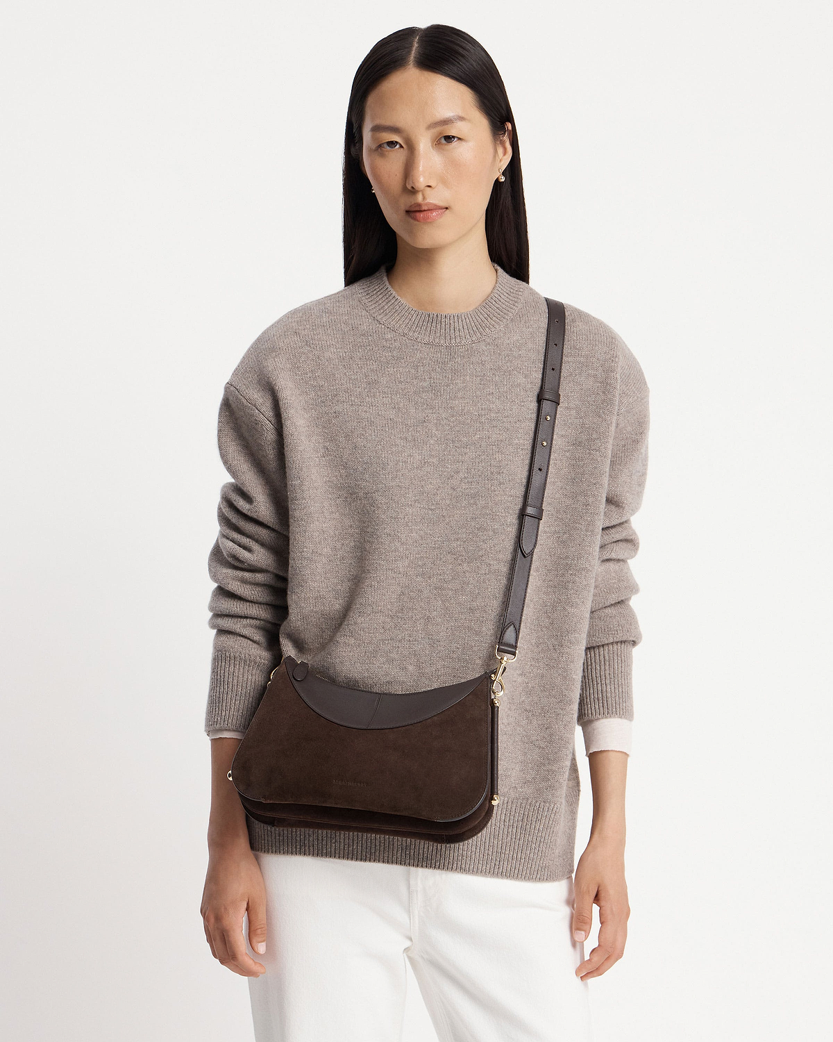Model wearing Nest shoulder bag in espresso suede with adjustable strap across chest.