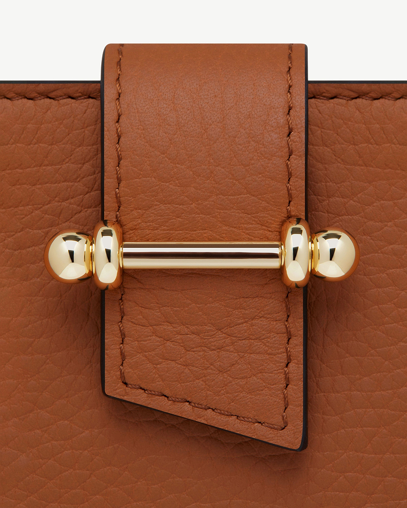 Tan pebbled leather passport holder strap with a polished gold bar clasp