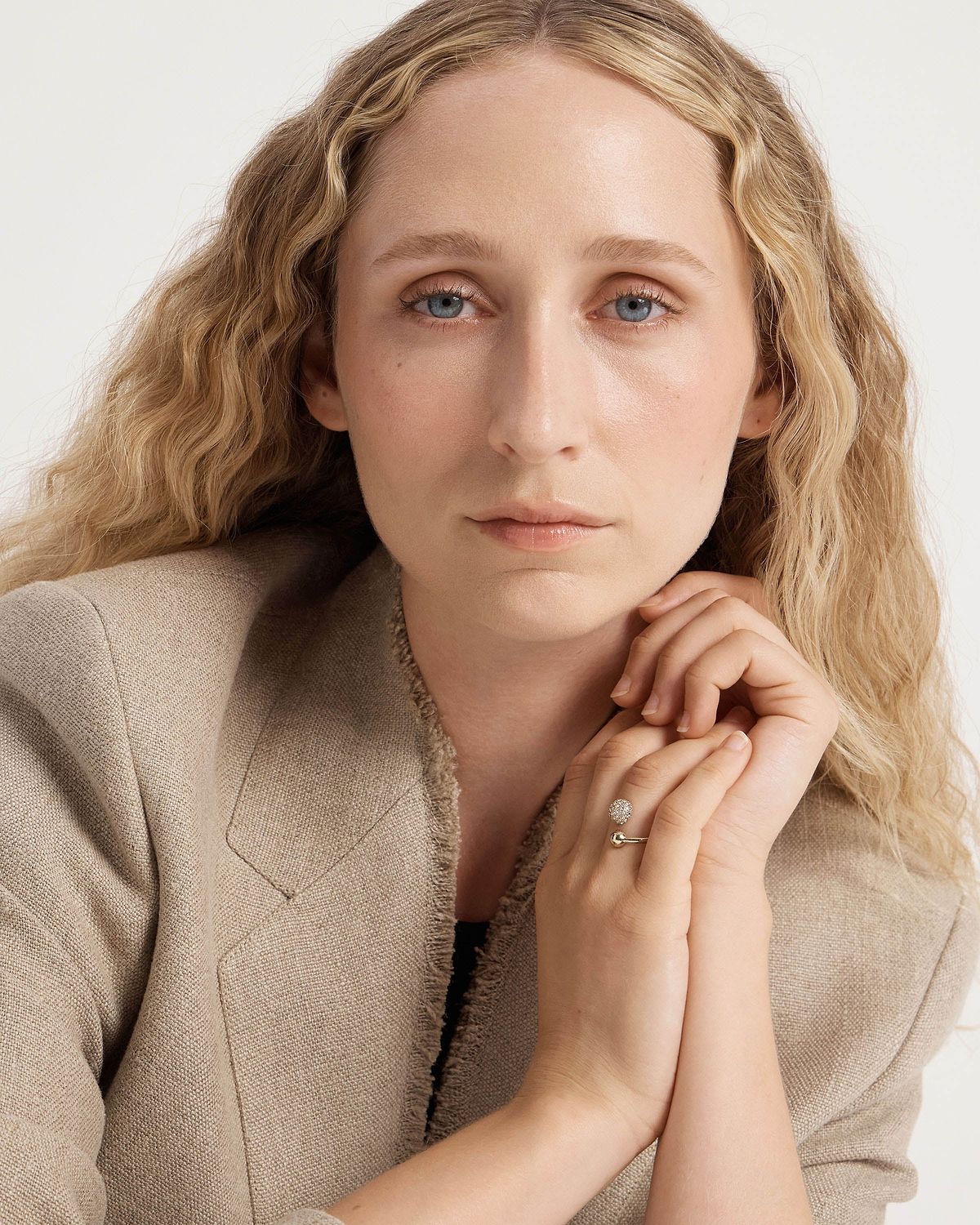 Woman's face and hands wearing a 22-carat gold-gilded crystal ring on her finger.