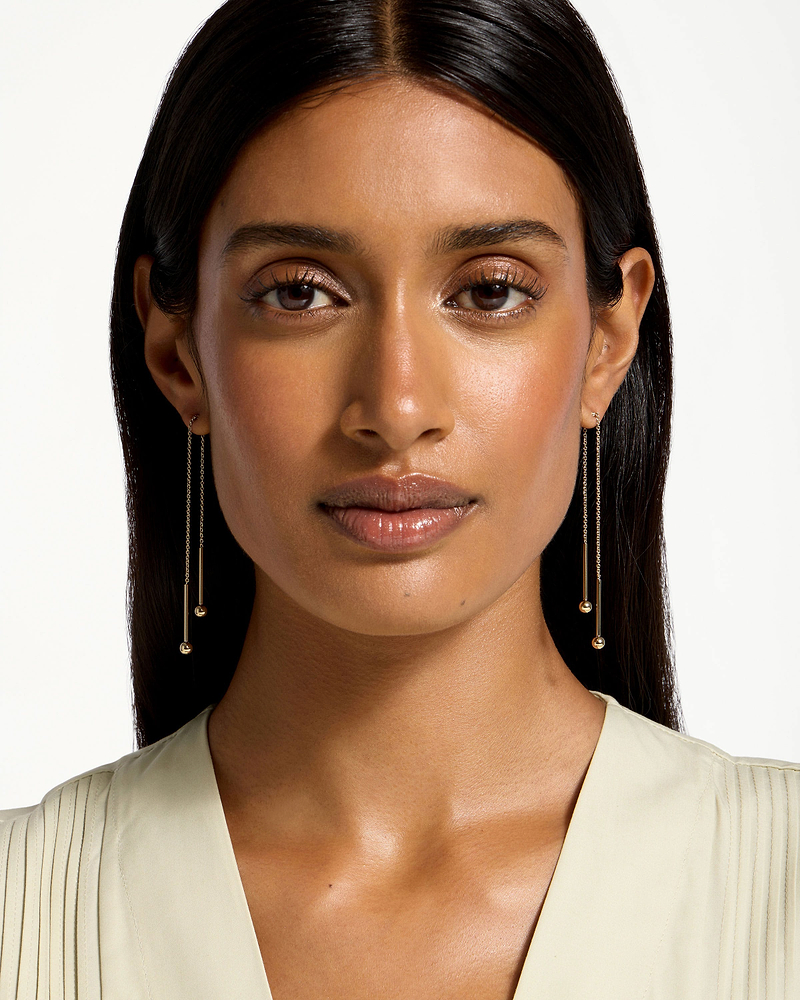 Model wearing 22-carat gold-gilded Essential earrings, long chain with small gold beads