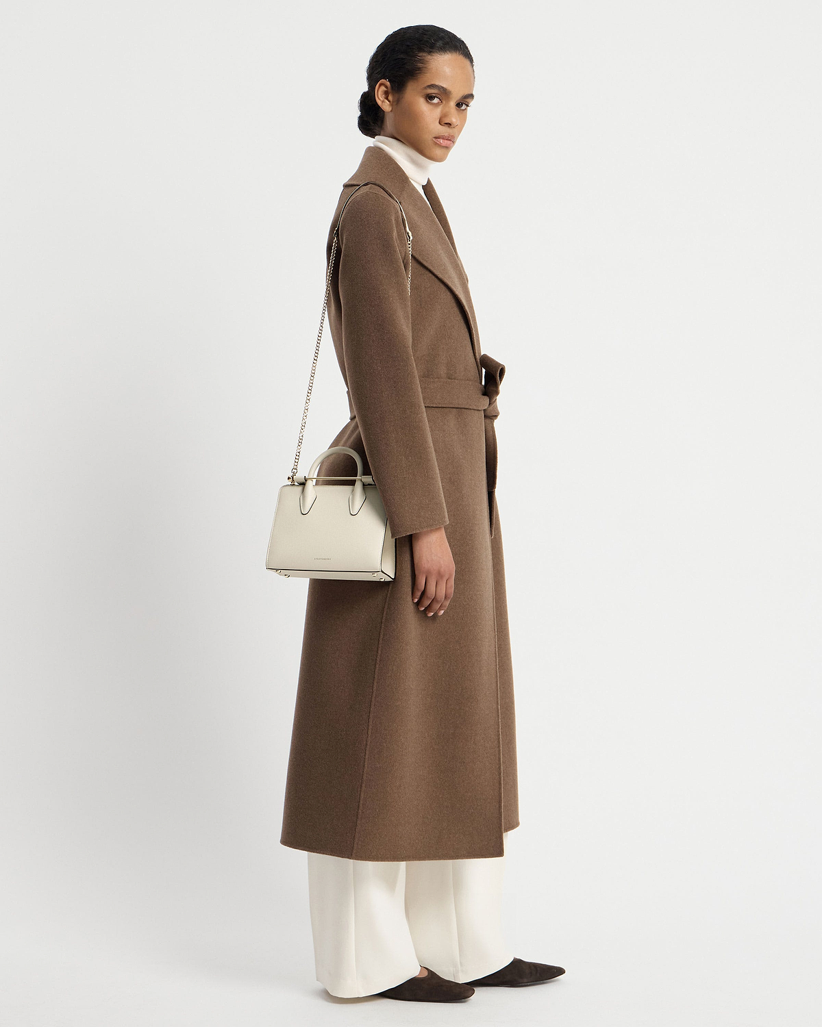 Model wearing a brown coat carrying a vanilla mini tote with chain shoulder strap.