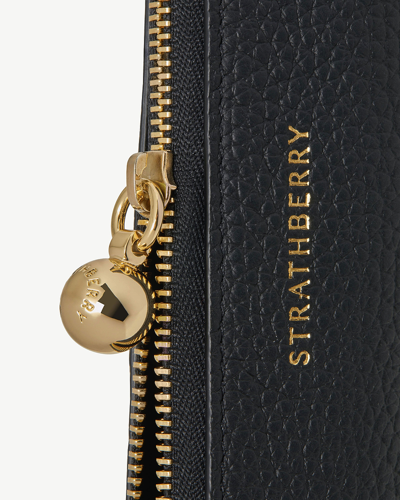 Black pebble leather pencil case with gold zip pull and Strathberry logo.