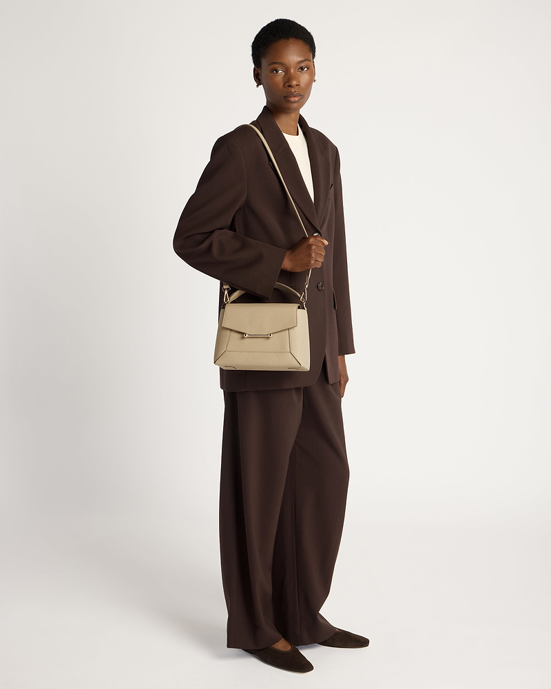Model wearing a brown blazer holding a sand mosaic bag by shoulder strap.