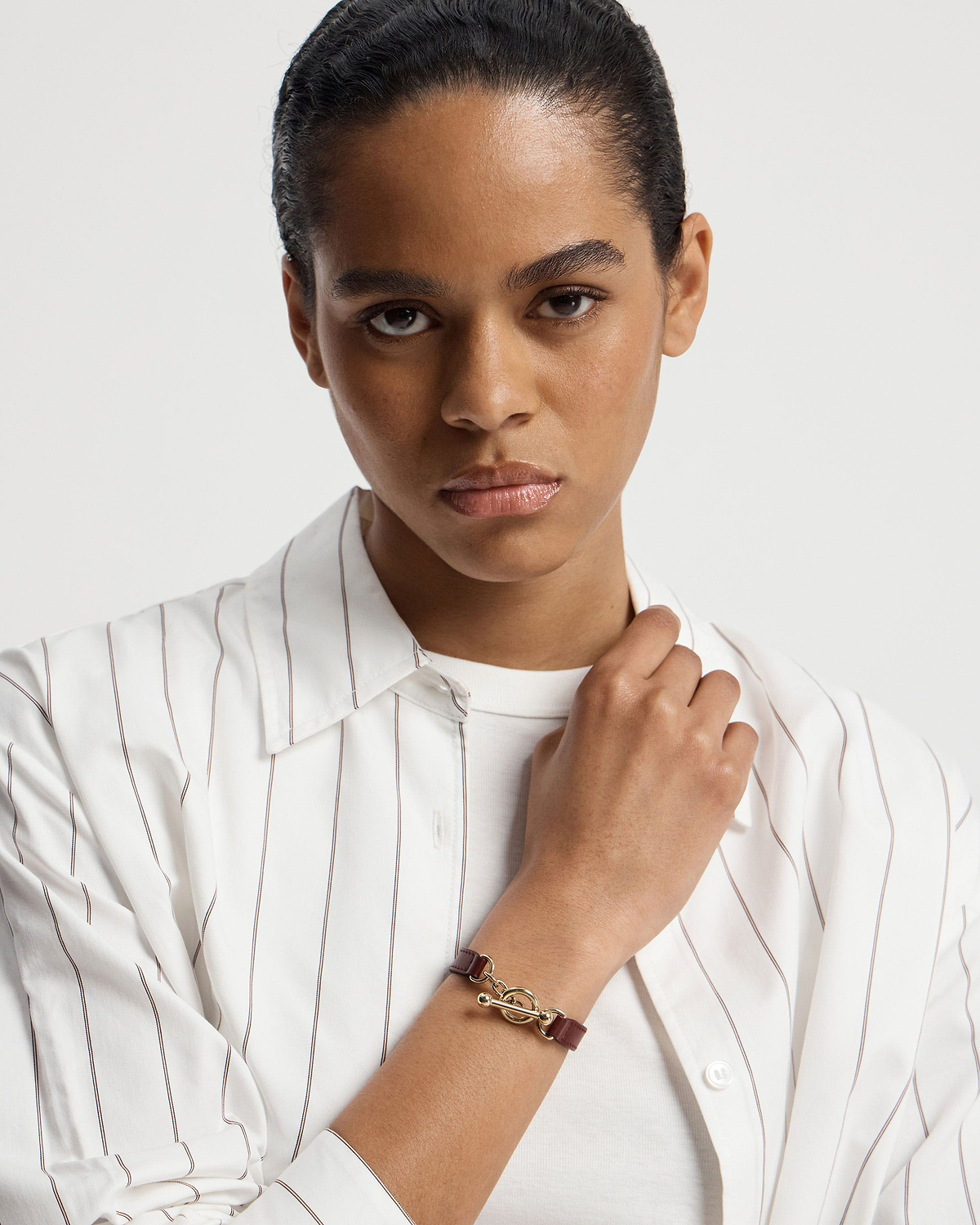 Model wearing oxblood leather kite bracelet with gold toggle clasp on wrist.